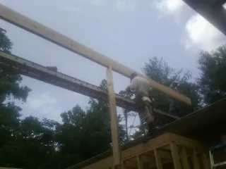 Carpenter setting a ridge beam over a new addition frame — Ice Dam Removal by Roofing Brothers in Wisconsin Rapids