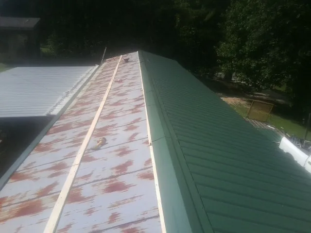 Old rusted panels beside newly installed green metal roofing — Wind Damage Roof Repair by Roofing Brothers in Wisconsin Rapids