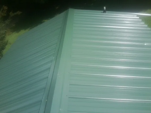 New green metal panels meeting at the ridge of a roof — Flat Roof Repair work by our crew in Wisconsin Rapids
