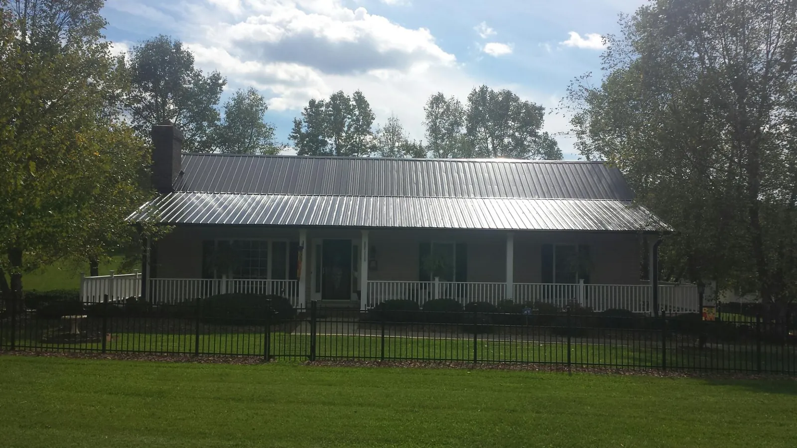 Gray metal roof on a brick ranch with a full width front porch — Gutter Guard Installation work by our crew in Wisconsin Rapids