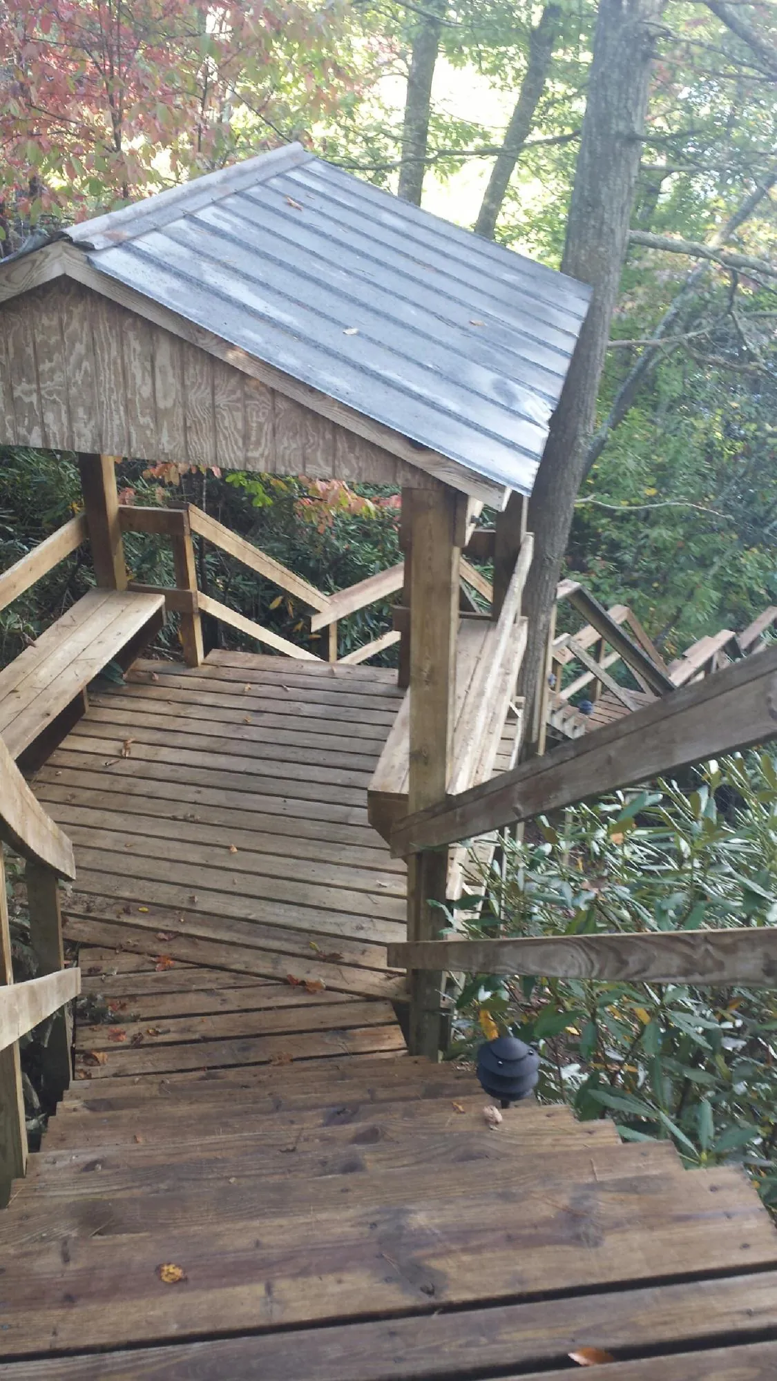 Metal roofed shelter over wooden steps on a wooded walkway — Skylight Repair & Installation work by our crew in Wisconsin Rapids