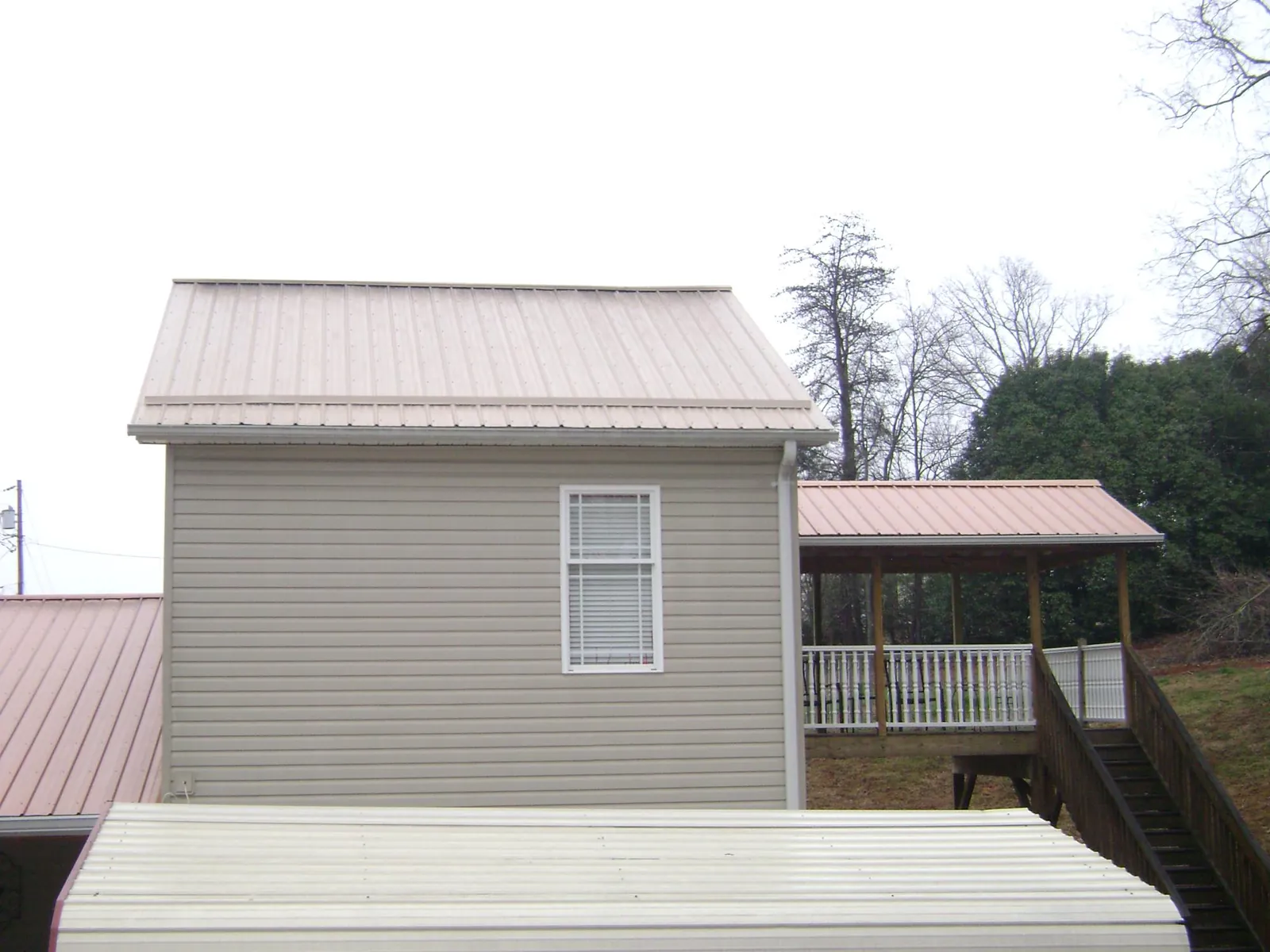 Tan metal roofs on a two story addition and attached porch, from a Roof Replacement job in Wisconsin Rapids