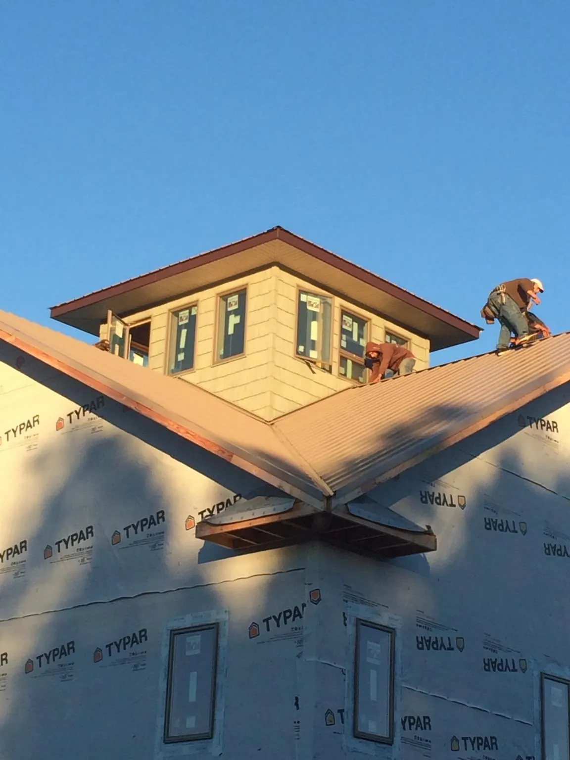 Roofers working around a rooftop cupola on a new metal roof at sunset — Roof Waterproofing in Wisconsin Rapids by Roofing Brothers